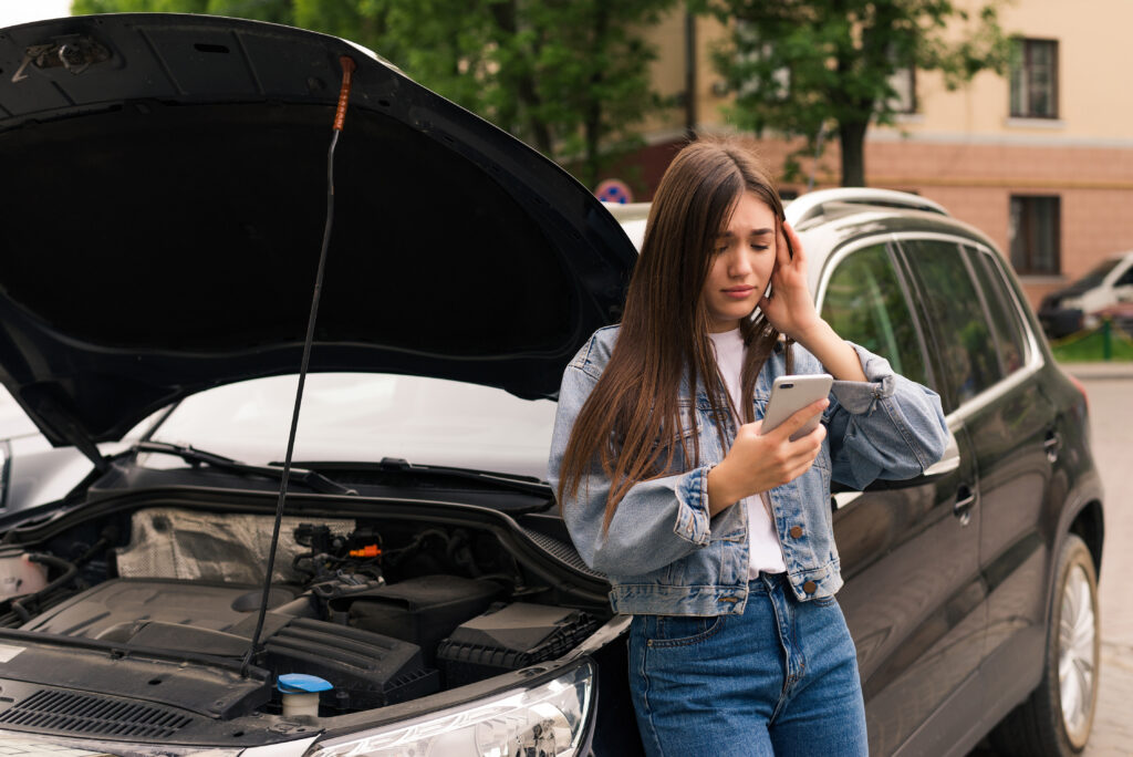 Young woman calling in evacuation service for her car broke down on the road.